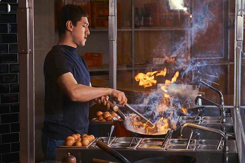 Chef cooking with oil in a restaurant.