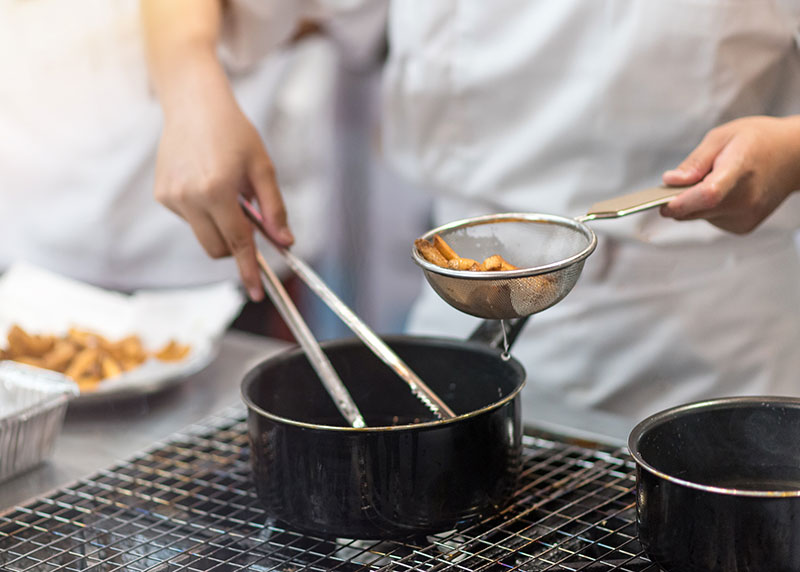 Chef is cooking french fries in the kitchen, cook preparing delicious French fries