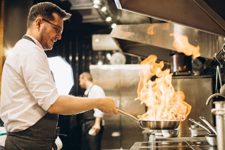 Chef cooking with oil in a commercial kitchen